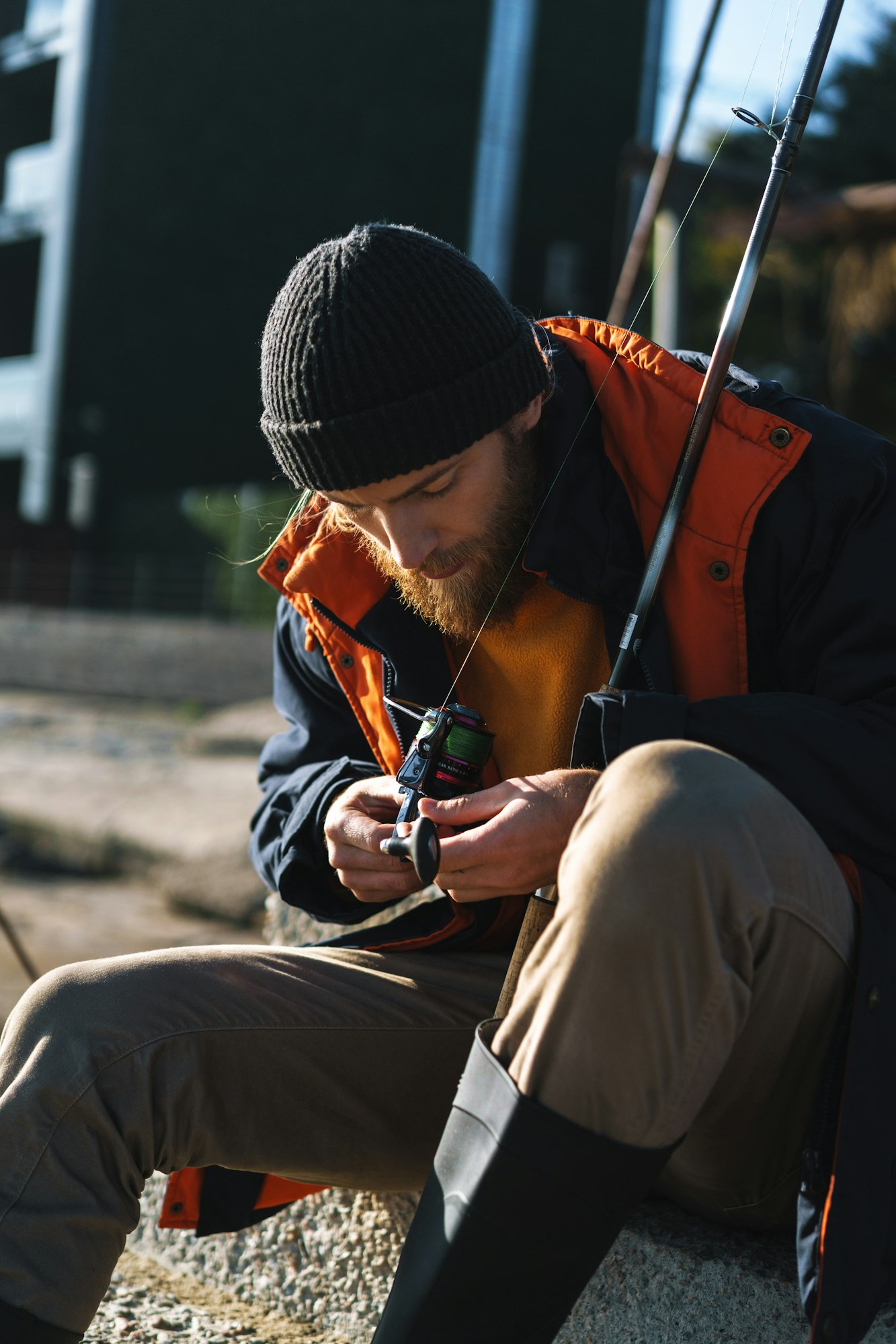 Handsome young man fisherman wearing coat and hat at the seashore.