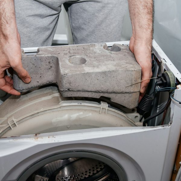 Handyman repairing a washing machine. The hands of a man repair a washing machine.