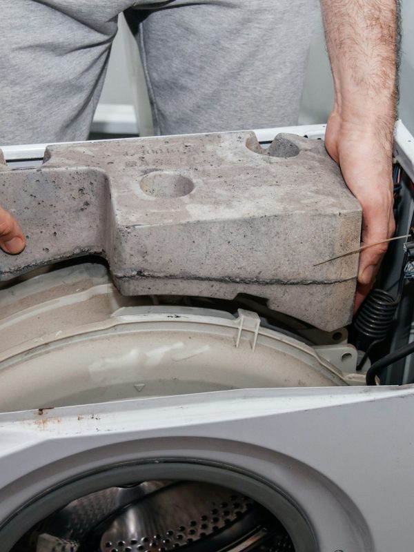 Handyman repairing a washing machine. The hands of a man repair a washing machine.